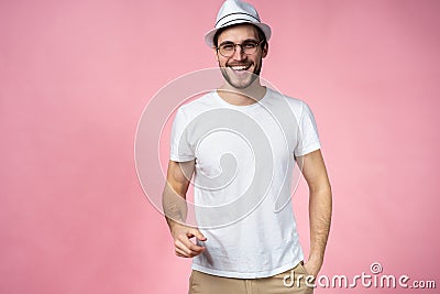 Cheerful hipster guy smiles happily, has excited expression, dresssed casually isolated over pink studio background Stock Photo