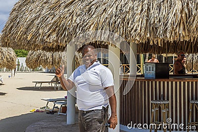 Cheerful hotel staff member near the beachside restaurant, warmly smiling and giving a thumbs-up Editorial Stock Photo