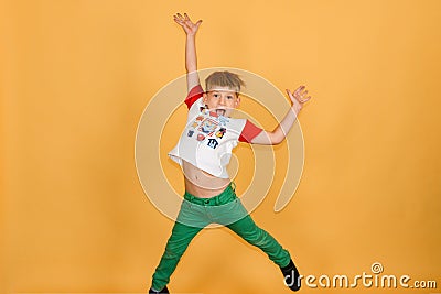 A cheerful and joyful boy is jumping up on a yellow background in the studio Stock Photo