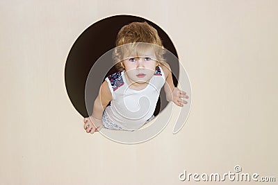 Boy half climbed out into the round window and smiles contentedly right into the frame Stock Photo