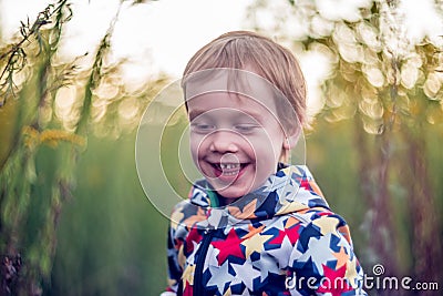 Cheerful kid toddler laughing outdoors. Child portrait in nature. Caucasian White boy. Stock Photo