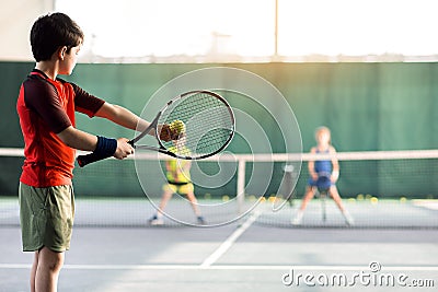 Cheerful kids playing tennis on court Stock Photo