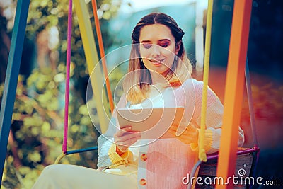 Happy Woman Relaxing in Garden Swing Holding a Tablet Stock Photo