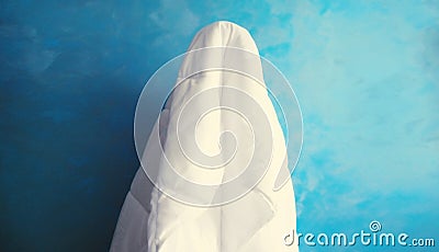 Cheerful lazy woman waking up after sleeping covered head with white blanket on blue background at home Stock Photo