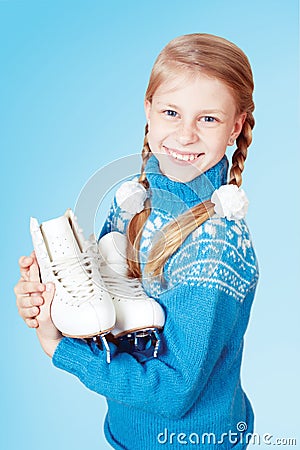 Cheerful little girl in blue warm sweater holding figure skates. Stock Photo