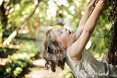 Cheerful, little girl climbing on a palm tree Stock Photo