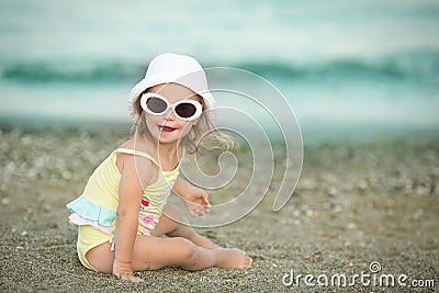 Cheerful little girl with Down syndrome with glasses resting on the sea coast Stock Photo