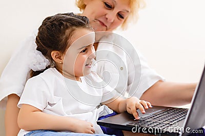 Cheerful little girl and grandma using laptop at home Stock Photo