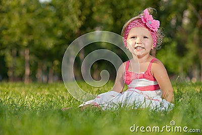 Cheerful little girl on the grass in the park Stock Photo