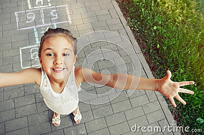 Cheerful little girl playing hopscotch on playground Stock Photo