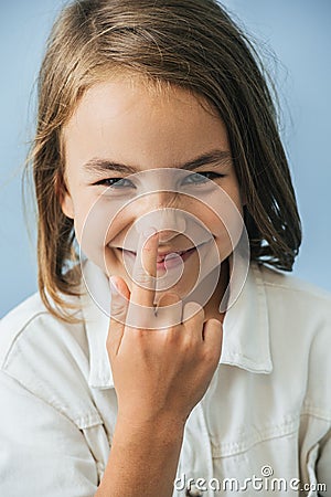 Cheerful little girl in a white shirt touching nose with her finger Stock Photo