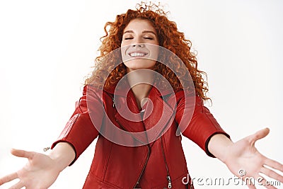 Cheerful lovely dreamy redhead curly-haired woman modern stylish red jacket extend arms close eyes ready kisses hugs Stock Photo