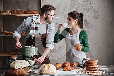 Cheerful loving couple bakers drinking coffee. Looking aside. Stock Photo