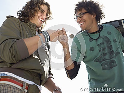 Cheerful Male Skateboarders Giving A Fist Bump Stock Photo