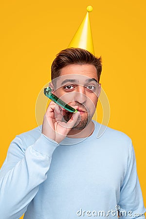 Cheerful man blowing noisemaker during party Stock Photo