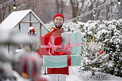 Cheerful man with gift boxes on winter time outdoors Stock Photo