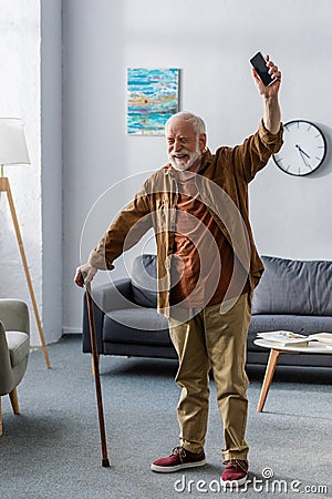 Cheerful man with walking stick holding Stock Photo