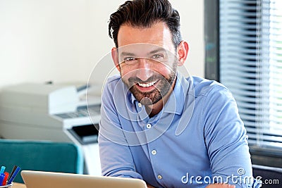 Cheerful middle aged guy sitting at his desk Stock Photo