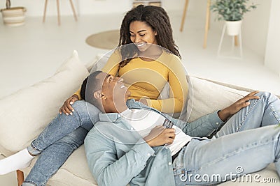 Cheerful millennial african american couple with remote control enjoy free time and tender moment, relaxing Stock Photo