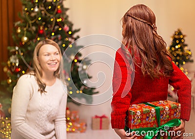 Cheerful mom and her cute daughter girl exchanging gifts. Merry Christmas and Happy Holidays. Stock Photo