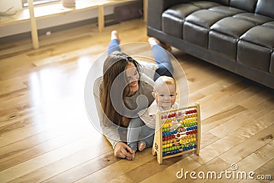Cheerful mother playing with his baby girl on floor at living room Stock Photo
