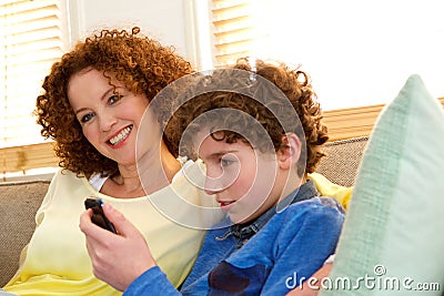 Cheerful mother sitting with son playing games on his phone Stock Photo