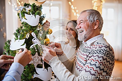 Multi-generation family indoors at home at Christmas, decorating tree. Stock Photo
