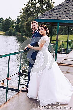 Cheerful newlyweds stand on the pier in an embrace Stock Photo