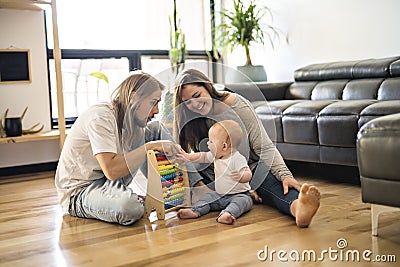 Cheerful parent playing with his baby girl on floor at living room Stock Photo