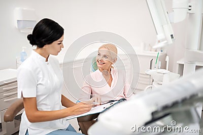 Cheerful patient asking her dentist about procedures. Stock Photo