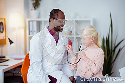 Cheerful pediatrician feeling good communicating with girl Stock Photo