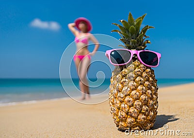 Cheerful pineapple glasses and a woman in a bikini sunbathing on the beach on sea backgrounde beach on sea background. Stock Photo