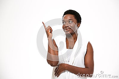 Cheerful pretty african american young woman standing and pointing up Stock Photo