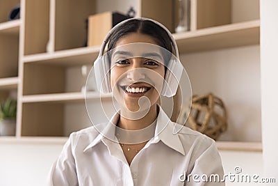 Cheerful pretty Indian manager girl in headphones looking at camera Stock Photo