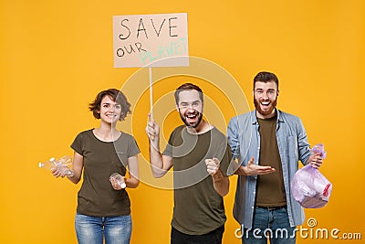 Cheerful protesting young three people hold protest broadsheet placard plastic bottles trash bag isolated on yellow Stock Photo