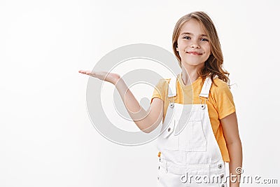 Cheerful proud cute little girl showing achievement, introduce cool copy space, raise hand hold something on blank space Stock Photo