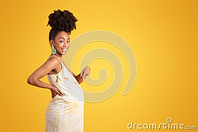 Cheerful proud millennial african american lady pointing finger at big belly Stock Photo