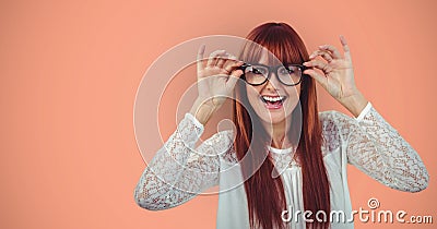Cheerful redheaded female hipster wearing eyeglasses against orange background Stock Photo