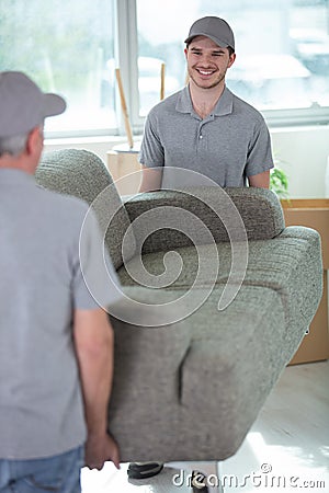 cheerful removals men carrying sofa Stock Photo