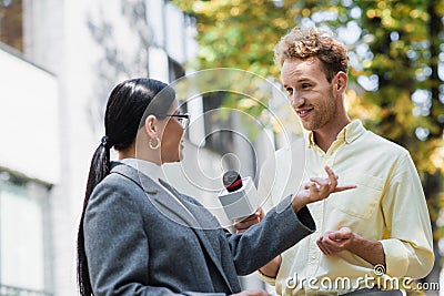 cheerful reporter holding microphone near asian Stock Photo