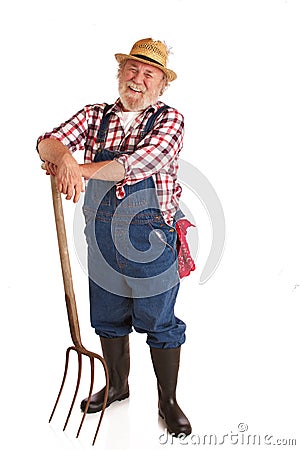 Cheerful senior farmer leaning on hay fork Stock Photo