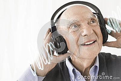 Cheerful senior man listening music through headphones against white background Stock Photo