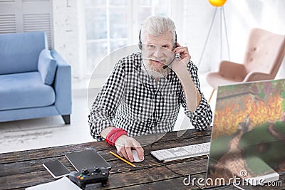 Cheerful senior man playing multiplayer game and smiling Stock Photo