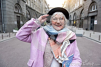 Cheerful senior woman standing with magazine about traveling Stock Photo