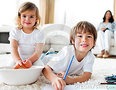 Cheerful siblings eating chips and drawing Stock Photo