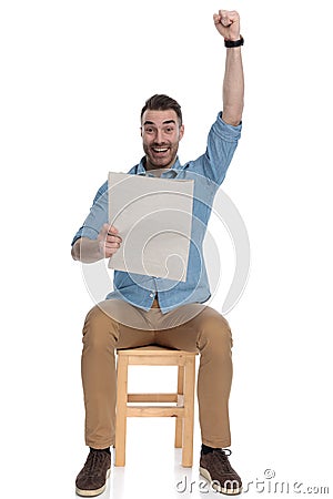 Cheerful smart casual man holding newspaper and celebrating, laughing Stock Photo