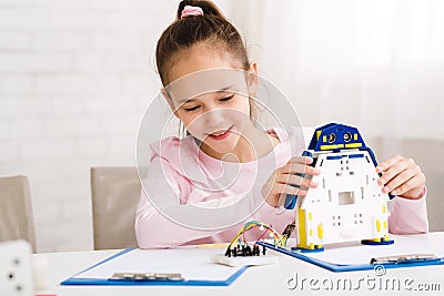 Cheerful smart schoolgirl constructing robotic device at lesson Stock Photo