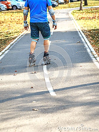 Cheerful sporty man 50-55 years old riding the roller skating in park in autumn season, rollerblading as healthy exercise for all Stock Photo