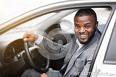 Cheerful successful black businessman looking through car window Stock Photo