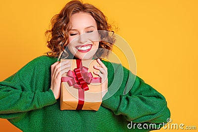 Cheerful surprised woman laughs with closed eyes holds a Christmas gifts on a colored yellow background Stock Photo